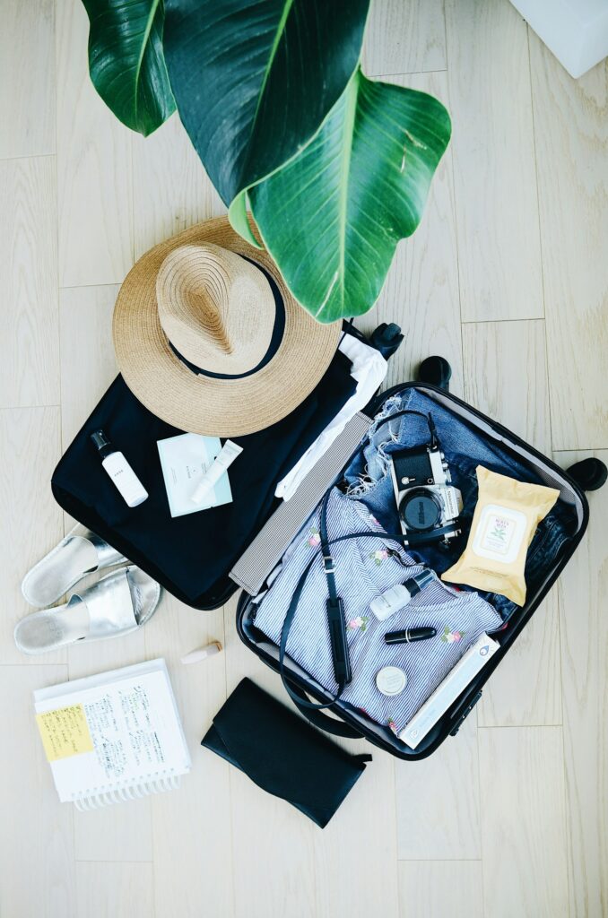 Open suitcase packed for safari with a sun hat and travel essentials