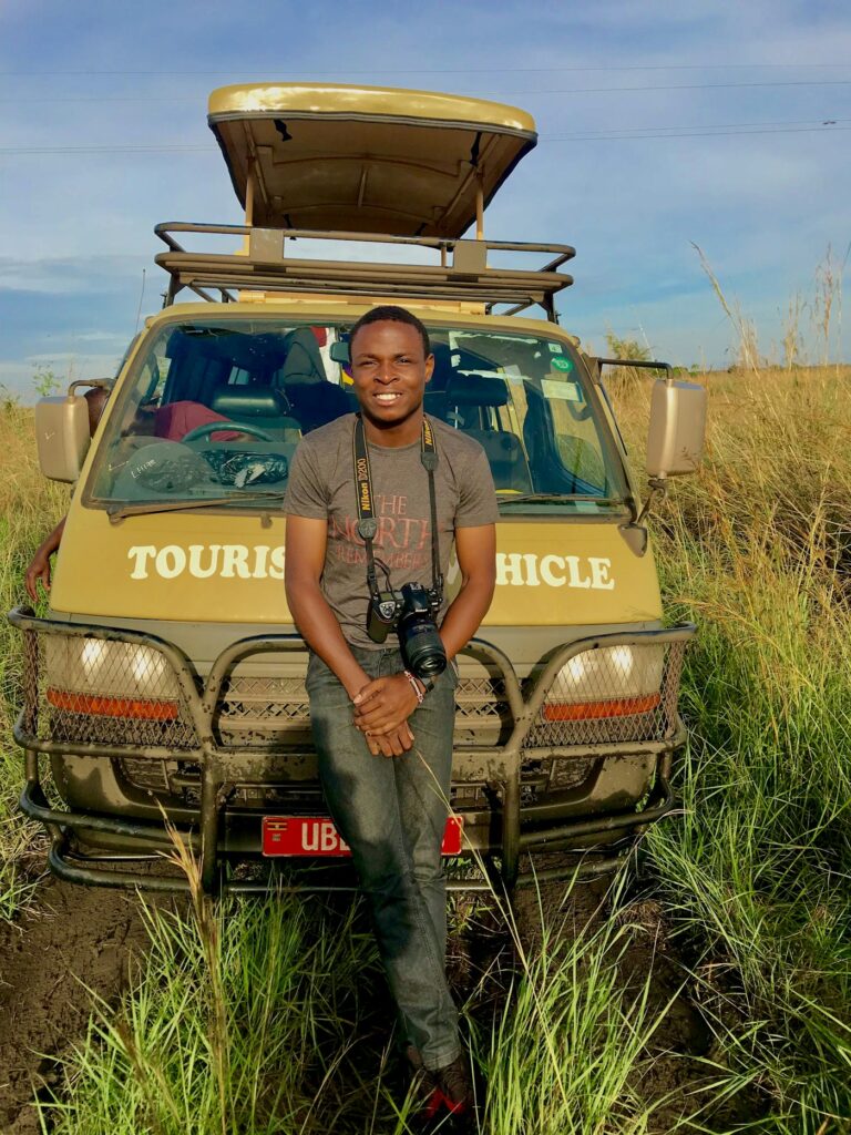Traveller with a camera beside a yellow safari vehicle